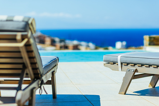 Sunbeds next to the pool at luxury apartment, Elia, Mykonos island, Cyclades, Greece. Property released.