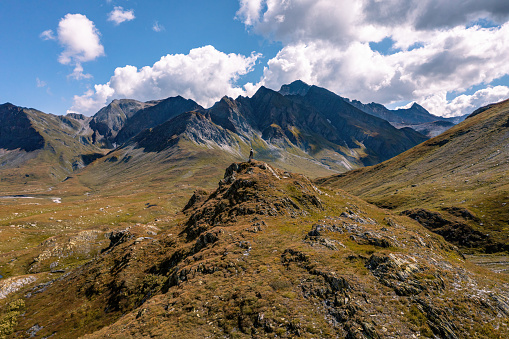 Aerial view toward a man at the tip of a rock formation admiring the vast and majestic alpine landscape, directed toward Piz Ner and Piz Canal, on the Piani della Greina, in Blenio, Switzerland. High quality photo.