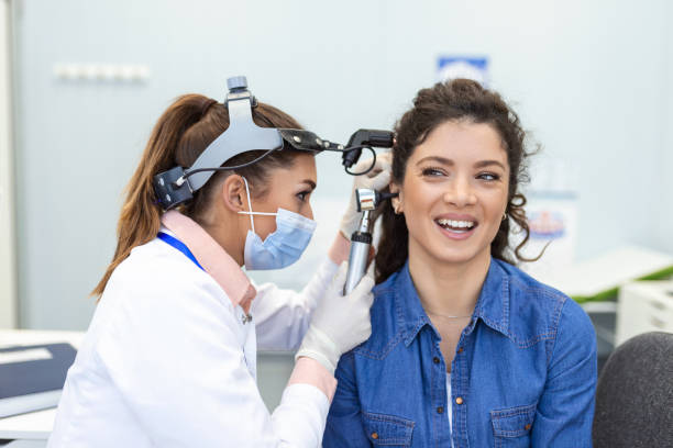 exame auditivo. médico otorâneo verificando o ouvido da mulher usando otoscópio ou auriscópio na clínica médica. otorrinolaringologista puxando a orelha com a mão e olhando para ela com close-up otoscópio. - aparelho auditivo - fotografias e filmes do acervo