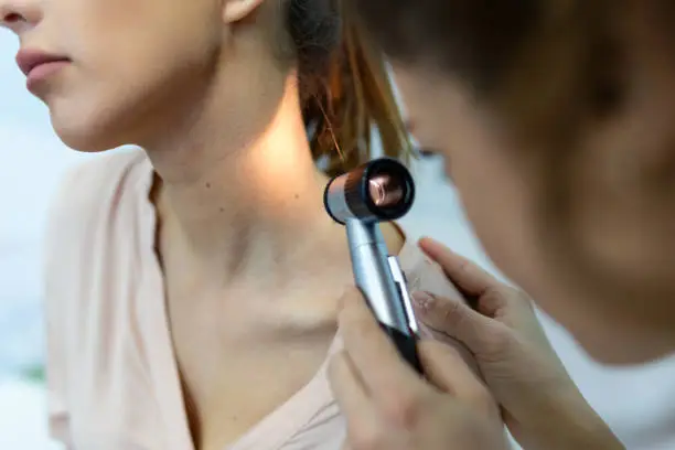 Photo of Doctor dermatologist examines skin of patient. Dermatoscopy, prevention of melanoma, skin cancer.