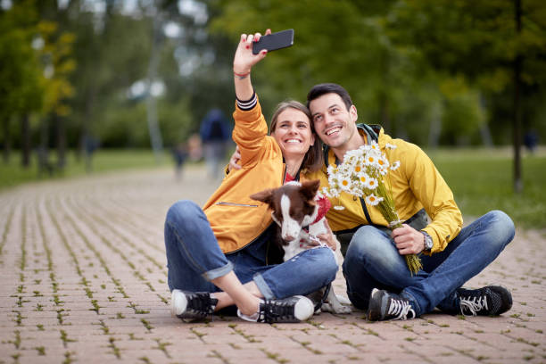istock young couple taking selfie with a dog sitting on a path in park 1374786766