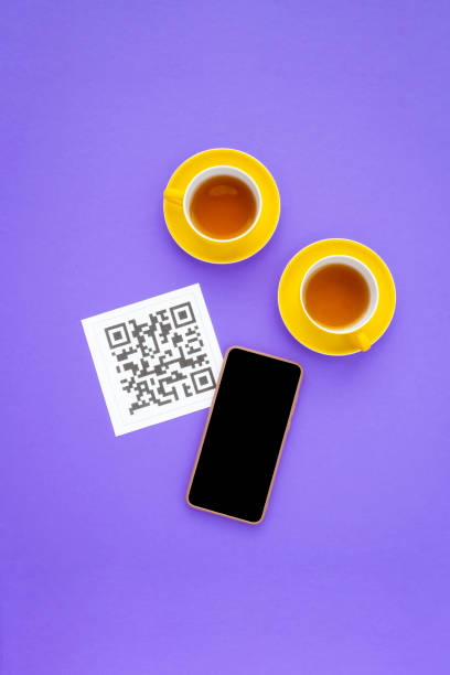 QR code for online menu at a table in a restaurant. QR code, phone, cups of tea on purple background