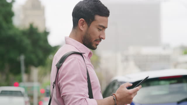 4k video footage of a young businessman using his cellphone while making his way to work