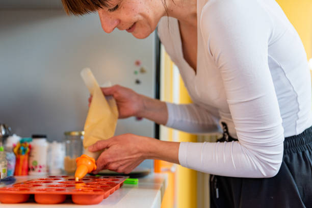 istock Woman in Domestic Kitchen Pouring Donuts Dough into Molds 1374788016