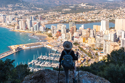 A hiker with a hat in the Peñón de Ifach Natural Park in the city of Calpe, Valencia, Valencian Community. Spain. Mediterranean sea. View of the Cantal Roig and La Fossa beach