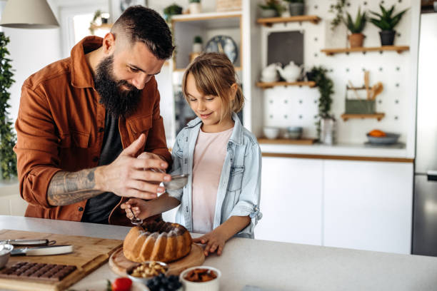 istock Father teaches daughter how to decorate a cake 1374809266