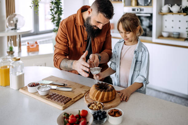 istock Father teaches daughter how to decorate a cake 1374809660