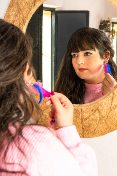 istock Woman trying on colorful handmade earrings using a mirror at home. 1374810321