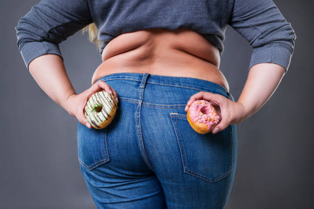 fat woman posing with donuts on a gray background - kvinna stor rumpa bildbanksfoton och bilder