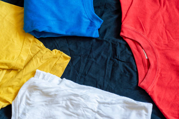 istock Background and casually lying multi-colored t-shirts with empty space for text in the middle. Template with cotton fabric. 1374811936