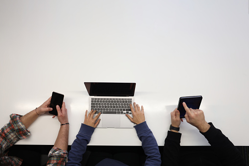 Top view of colleagues working with laptop, tablet and mobile phone during meeting