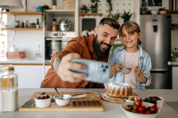 istock Father and daughter taking a selfie while decorating a cake in the kitchen 1374812473