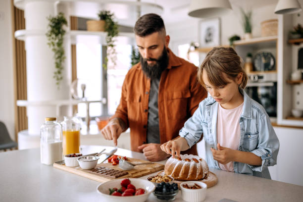 istock Father and daughter putting a final touch on their cake 1374814082