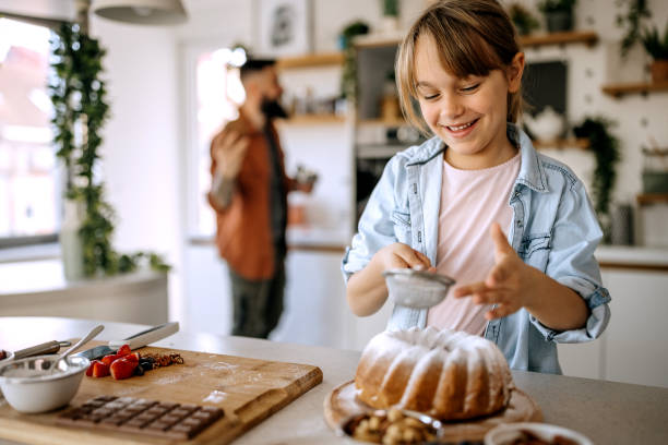 istock Cute little girl decorating a cake while her father is in the background 1374814610