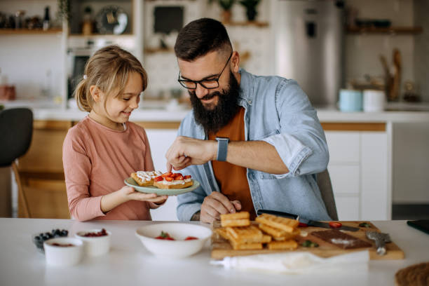 istock Father and daughter decorating a waffle with strawberries 1374817232
