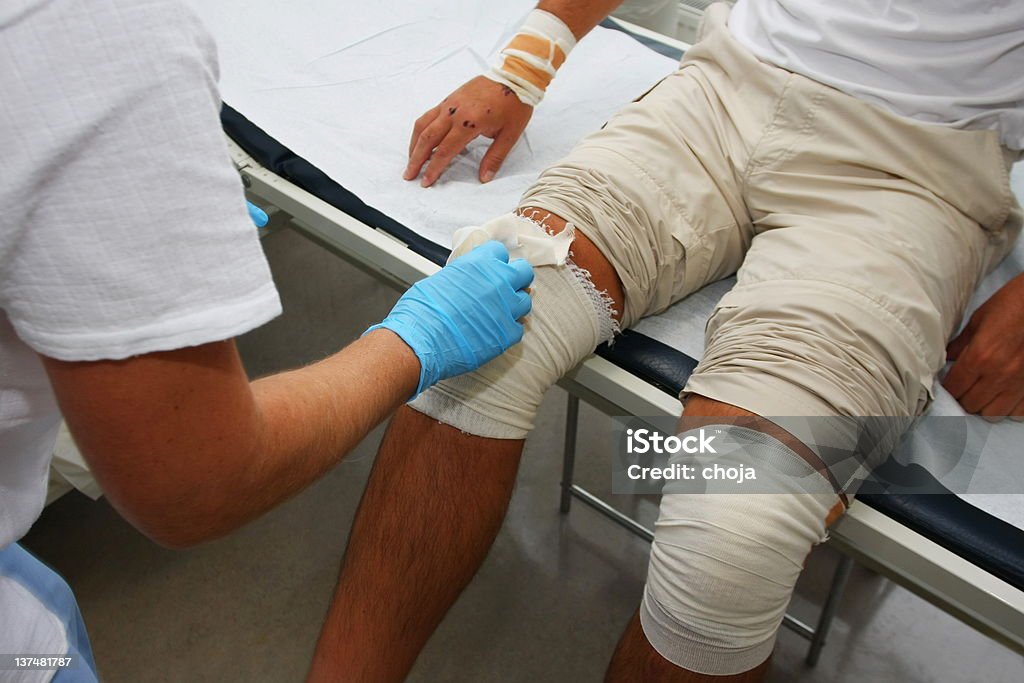 Enfermera es cuidar a los heridos donde la rodilla, cambiando vendaje - Foto de stock de Asistencia sanitaria y medicina libre de derechos