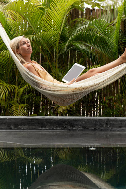 istock Woman relaxing in an hammock by the pool with a digital tablet 1374820397