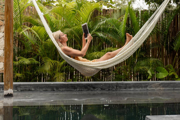 istock Woman relaxing in an hammock by the pool with a digital tablet 1374820917