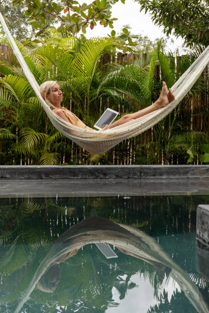 istock Woman relaxing in an hammock by the pool with a digital tablet 1374829737