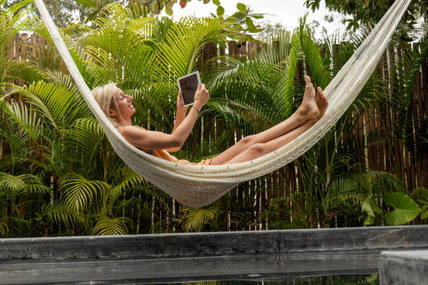 istock Woman relaxing in an hammock by the pool with a digital tablet 1374830082
