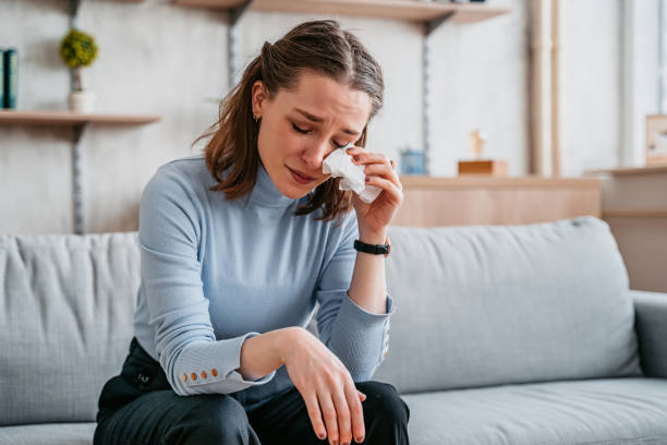 Young Woman Crying Beautiful young woman sitting on the sofa in the living room and crying. crying stock pictures, royalty-free photos & images