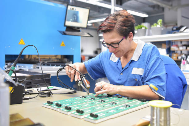femme sympathique travaillant dans une usine de fabrication de microélectronique - assemblage de composants et soudure - ouvrier à la chaîne photos et images de collection