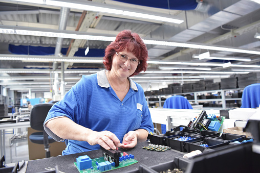 friendly woman working in a microelectronics manufacturing factory - component assembly and soldering