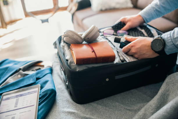 Packing for a business trip. Unrecognisable man packing his suitcase for a business trip. business travel stock pictures, royalty-free photos & images
