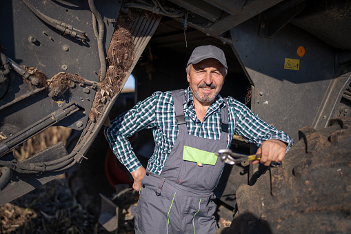 Portrait of senior mechanic repairing a combine.