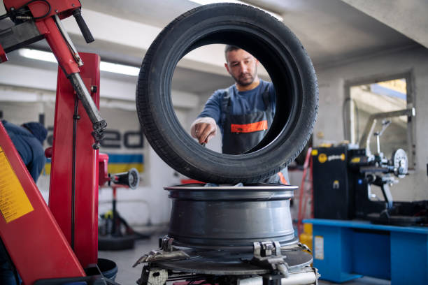 technicien changeant de pneu au centre de service de voiture de pneu. - automotive repair center photos et images de collection