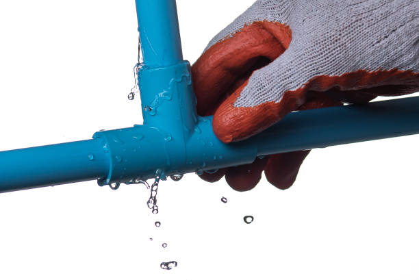 istock Man's hand holding blue pvc plastic pipe with a broken connection and water pouring out isolated on white background 1374881278