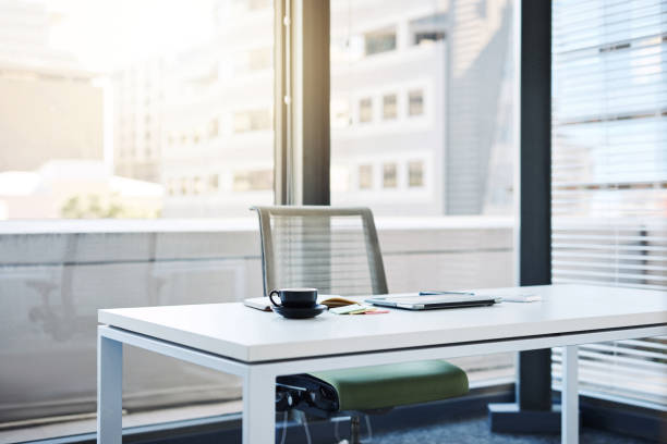 Office desk with a grey laptop with a blue sticky note and office supplies
