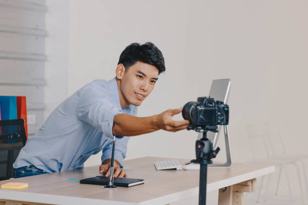 istock Young Asian man adjusts camera for shooting online contents. 1374905261