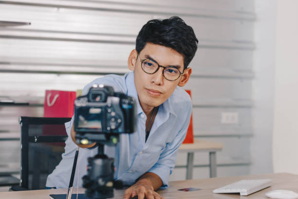 istock Young Asian man adjusts camera for shooting online contents. 1374917798