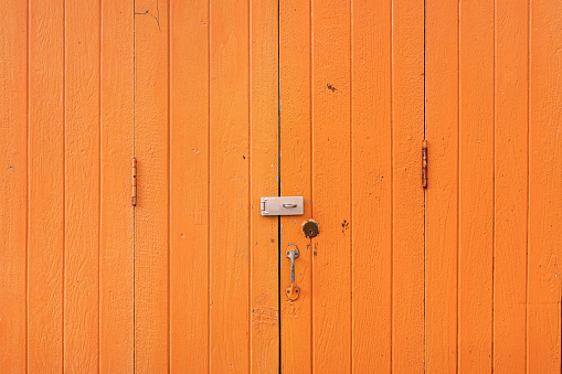 Background of old orange wooden doors with rough texture closed without key lock.