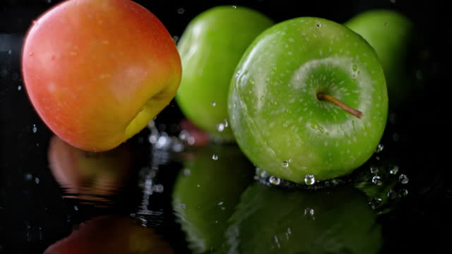 SLO MO Apples falling onto a wet surface and rolling across it