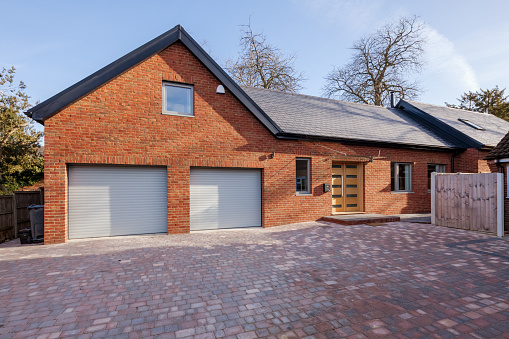 Modern contemporay brick built home in dappled sunlght with brick driveway