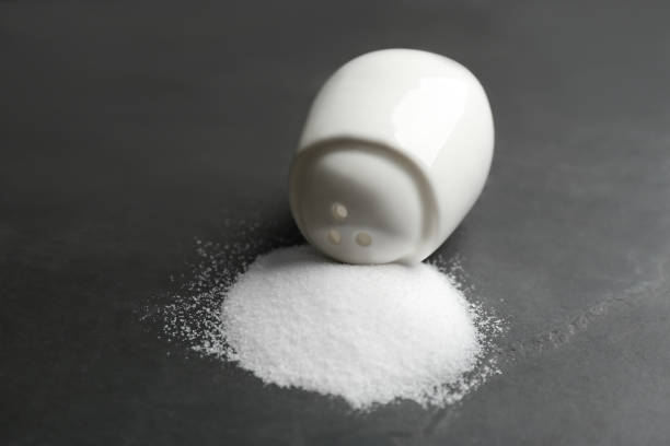istock Scattered salt and shaker on black table, closeup 1374958374