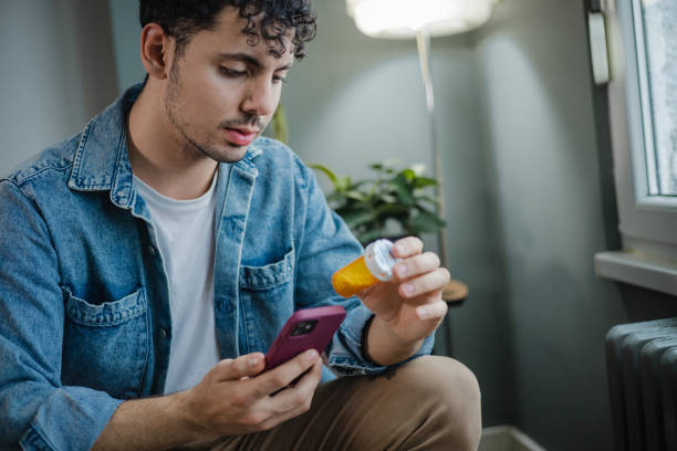 joven lee sobre medicina en línea - pill bottle fotos fotografías e imágenes de stock