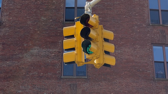 A yellow traffic light hangs at an intersection in New York, USA. Red stop signal. Traffic management on the road. Transport in the city. Stoplight.