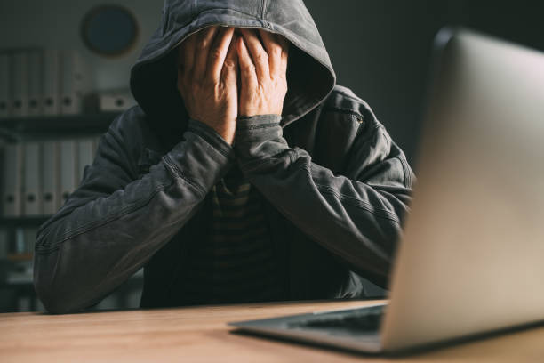istock Regretful computer hacker covering face with hands in front of laptop 1375013109