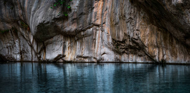 clear blue water in a deep canyon with sheer rock walls.