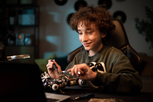 istock A boy works to create a fully functional robot from scratch. A bright teenager soldering with concentration and deteromputation at his desk repairs electronic equipment wires 1375016939