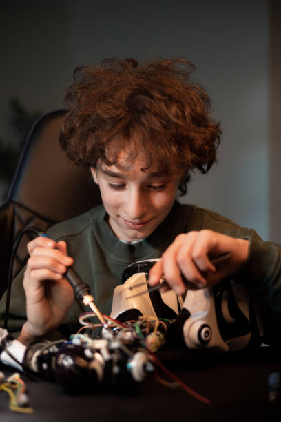 istock The child develops manual skills, plays with electronics, pulls wires with a tweezers, solders, repairs the robot's remote control system 1375016961