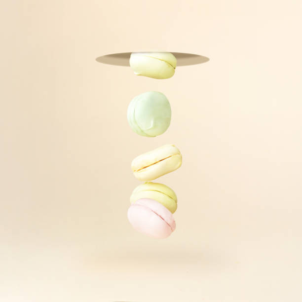 Different types of macaroons marshmallow in motion falling down on pastel coral background. oncept of sweet dessert.