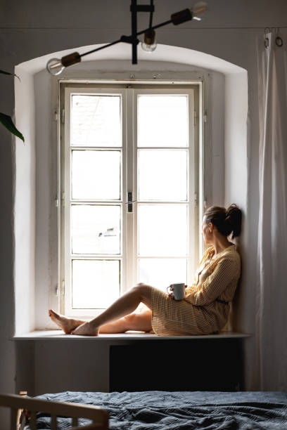 istock Young woman sitting and looking through window 1375032732