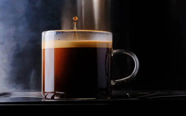 Photo of glass cup of espresso hot coffee with water coffee drop