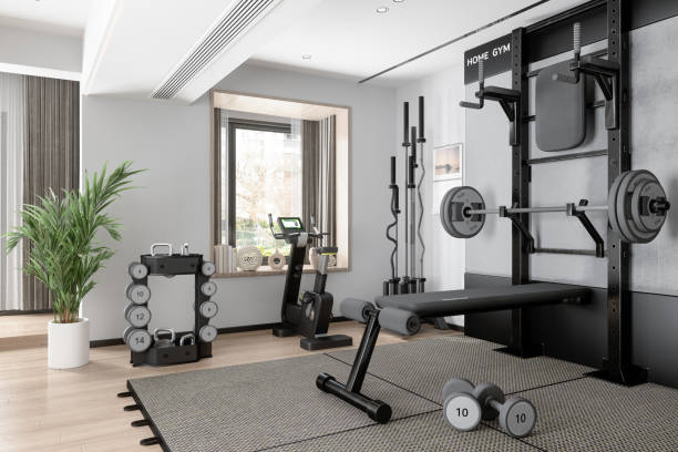 home gym mit langhantel, hanteln, heimtrainer und anderen sportgeräten - fitnessausrüstung stock-fotos und bilder