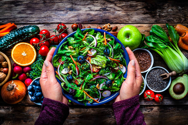 Woman hands holding salad plate on rustic table