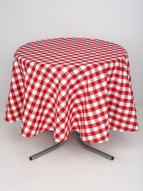 red checkered tablecloth spread out on a round table on a white background stock photo